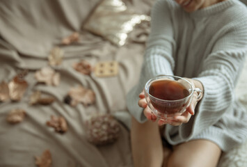 Fototapeta na wymiar Close-up of a glass cup of tea on a blurred background in female hands.