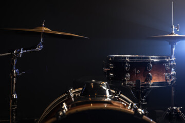 Drum kit in the dark with stage lighting, copy space.