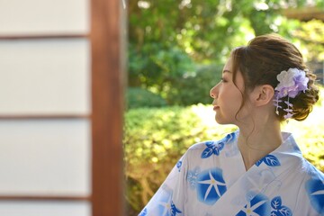 古民家の縁側でたたずむ美しい浴衣姿の若い女性