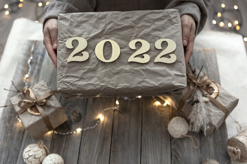 Close up of wrapped New Year gift with numbers 2022 in female hands.