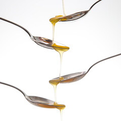 Fresh flower honey drips from a spoon into a spoon on a white background. Organic vitamin food.