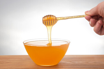 fresh honey dripping from a spoon into a transparent plate on a white background. organic vitamin health food