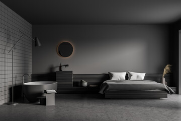 Dark bedroom interior with large bed, bathtub, grey empty wall