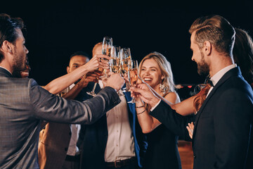Group of beautiful people in formalwear toasting with champagne and smiling while spending time on luxury party