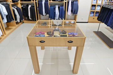Plakat Showcase with accessories in a men's clothing store. In the background are pants, suits, shirts, ties on shelves and hangers