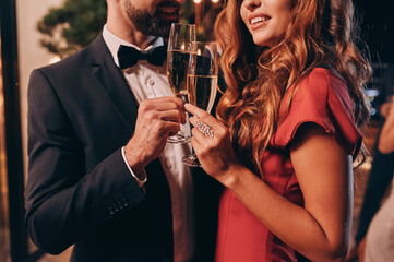 Close up of beautiful young couple in formalwear toasting with champagne while spending time on...
