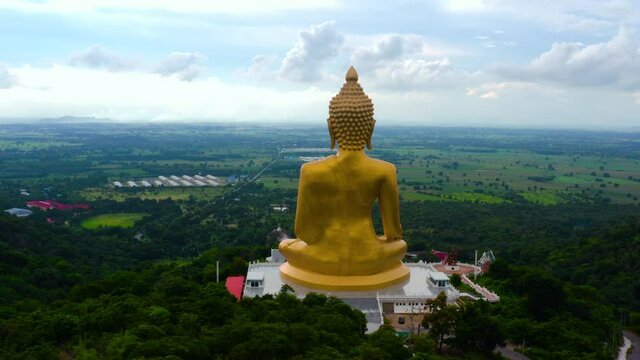 Aerial view of golden seated Buddha sitting in front of the mountain at Wat Khao wong prachan in Lopburi, Thailand