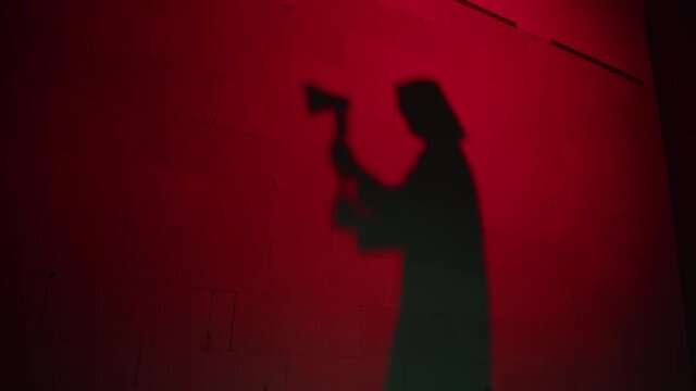Creepy death silhouette running for victim with axe on red background. Mystical scary murderer, maniac catching up woman. Halloween costume of killer. Horror scene movie of psycho serial. 