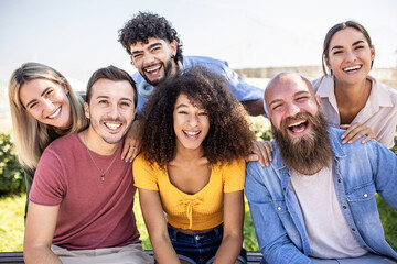 Multiracial group of young people - Happy millennial friends from different cultures smiling at smartphone camera - Friendship and youth concept with diverse millennial students sitting together