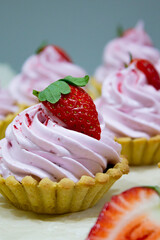 Array of delectable tartlets with rich pink cream, accented by fresh strawberries and a sliced berry, radiating gourmet charm.