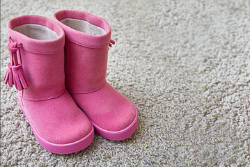 children's pink boots stand on the carpet. Copy space