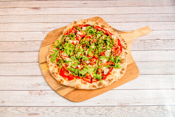 Pizza with melted mozzarella cheese, tomato sauce, arugula, goat cheese, olive oil and balsamic vinegar on wooden board