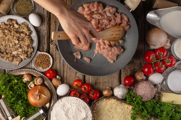 Beautiful composition. Ingredients. Lots of objects. Bright colors. The cook is frying pieces of chicken fillet in a skillet. Filling for pizza, pie. Cooking sauce, pasta.