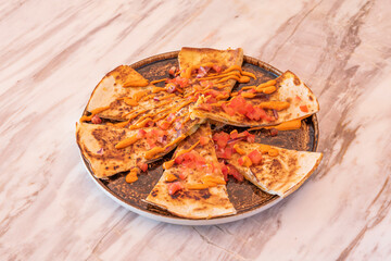 Quesadillas of cooked ham with cheddar cheese, pico de gallo and melted cheese on marble table