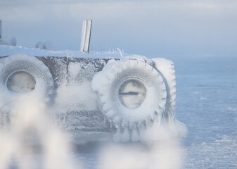 Ice covered boat docks with tractor wheels by the Baltic sea in Helsinki, Finland.