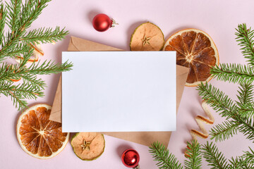 A holiday card with an envelope and a branch of a fir tree, oranges and Christmas toys.