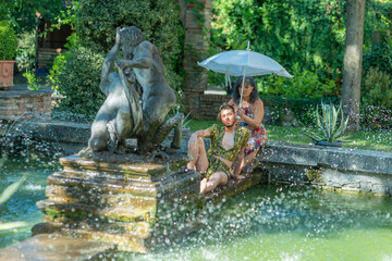 Fototapeta na wymiar diverse couple in a fountain staying cool in summer