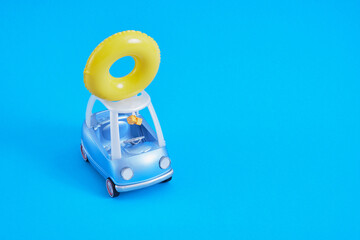 toy car and lifebuoy on the roof, swimming circle on the roof of a small blue golf car on a blue background