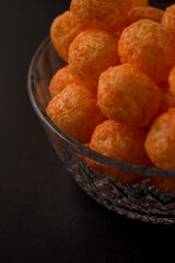 Cheese snack from a glass pot with cheese sticks and cheese balls on a black wooden table