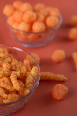Orange cheese snacks in glass pots on an orange surface 