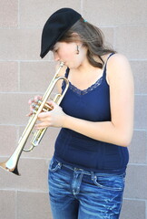 Female jazz trumpet player blowing her horn outside.