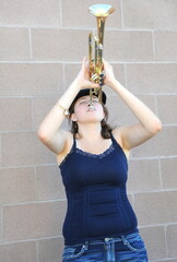 Female jazz trumpet player blowing her horn outside.