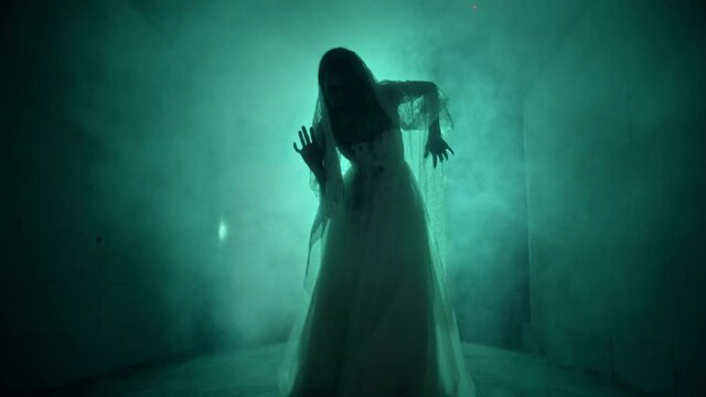 Dead walking zombie woman in dark corridor and mist close-up. Creepy bride wearing wedding dress with veil. Deceased fiancee returned to life. Horrible klip on halloween. Haunted house. 
