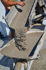 concrete falling from the hopper of the concrete mixer into a worker's forklift truck
