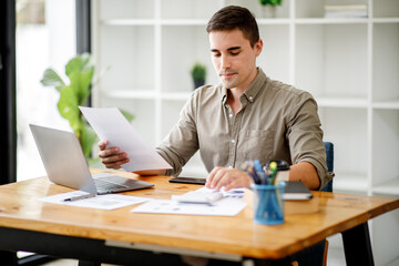 Fototapeta premium Young handsome man or businessman working on laptop computer in modern office.doing finances,accounting analysis,report,data and pointing graph Freelance education and technology concept.