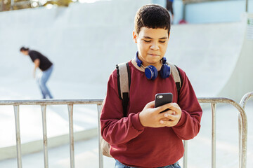 12 years old boy using smartphone outdoors.