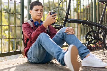 12 years old boy using smartphone outdoors.