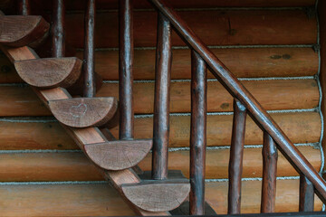 Close up of dark brown wooden stairs in log house outdoors.