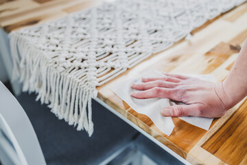 disinfecting surfaces from bacteria or viruses in your home or business, hand cleaning dining table with disinfectant wet wipe