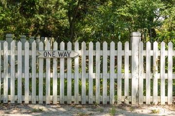 white fence and grass with a sign that says one way