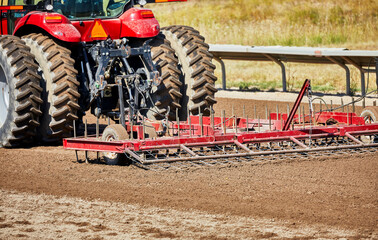 Tractor pulling a harrow on a dirt track