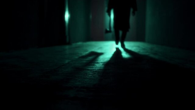 Maniac walking with axe in dark corridor. Mystical scary murderer going to kill, carrying murderous weapon. Halloween costume of killer. Horror scene or nightmare concept. 