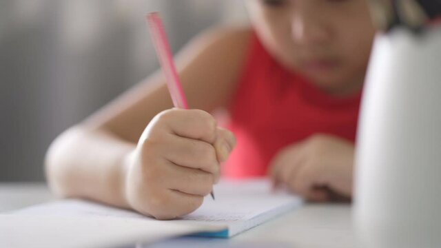 closeup hand of asian child writing learning or kid girl student doing homework on book to learn from homeschool and person training write on paper and desk by back to school to study online class