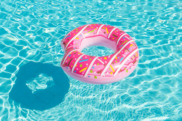 Inflatable children's playground in the form of a pink donut on the water in the pool