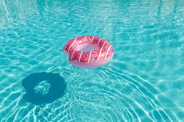 Inflatable children's playground in the form of a pink donut on the water in the pool