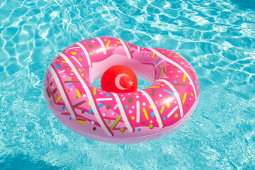 Inflatable children's playground in the form of a pink donut and a red ball in the form of the national flag of Turkey on the water in the poo