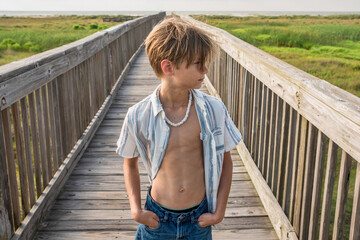 Male child with open shirt walking leisurely on beach boardwalk  © 3Days2Go Media
