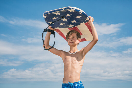 Male child swimmer carrying boogie board over his head on a sunny day