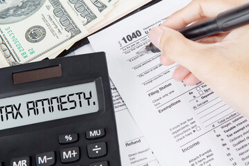 Hands filling tax form with tax amnesty text