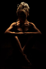 Fototapeta na wymiar Nude Woman silhouette in the dark. Beautiful Naked Body Girl sitting crossing legs. Sexy Naked sensual beautiful girl.