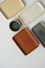 Neutral colour handmade ceramics, empty craft ceramic plates and bowls on white background. Flat lay, top view