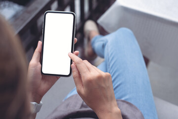 Cell phone mockup image blank white screen.  Woman hand holding, using mobile phone at home.