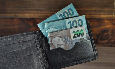 wallet with 100 reais and 200 reais banknotes on the wooden background. Brazil money, reais, real.