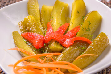 Fototapeta na wymiar Homemade pickled cucumber salad with roasted red peppers and fresh carrots. Pickels assortment