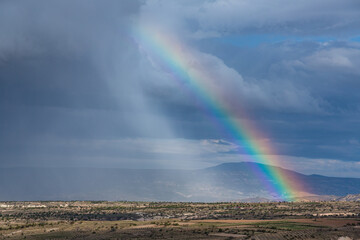 トルコ　カッパドキアのウチヒサールの丘から見える雨雲と虹がかかったギョレメ国立公園