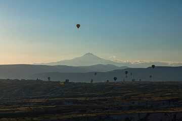 トルコ　カッパドキアのウチヒサール城から見える奇岩群とギョレメ国立公園の早朝の空を飛ぶ熱気球